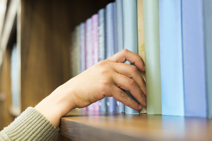 Hand pulling pastel book off of bookshelf