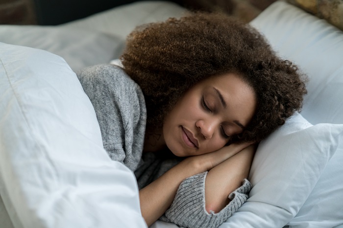 Woman sleeps peacefully with head resting on pillow.