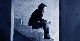 A woman sits alone on secluded stairs.