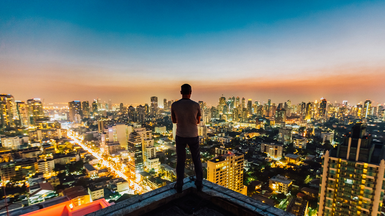 A man overlooks the bustling city from a rooftop.