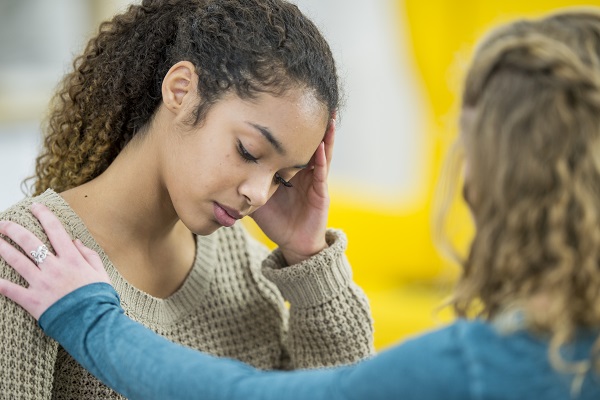 Woman comforts her friend, who has been bullied.