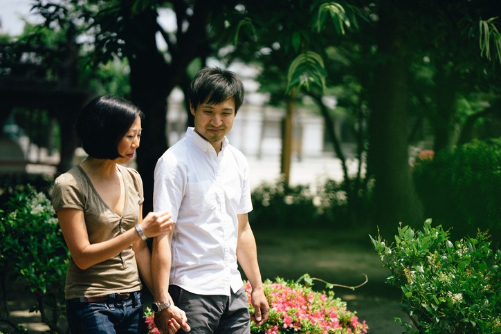 A couple walks hand-in-hand through a garden while having a deep discussion.