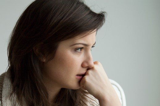 A worried woman covers her mouth with a fist.