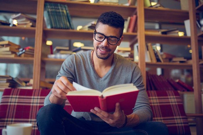 Man reading book on couch in a reading room