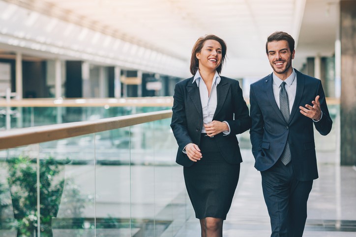 Male and female coworkers walk and talk.