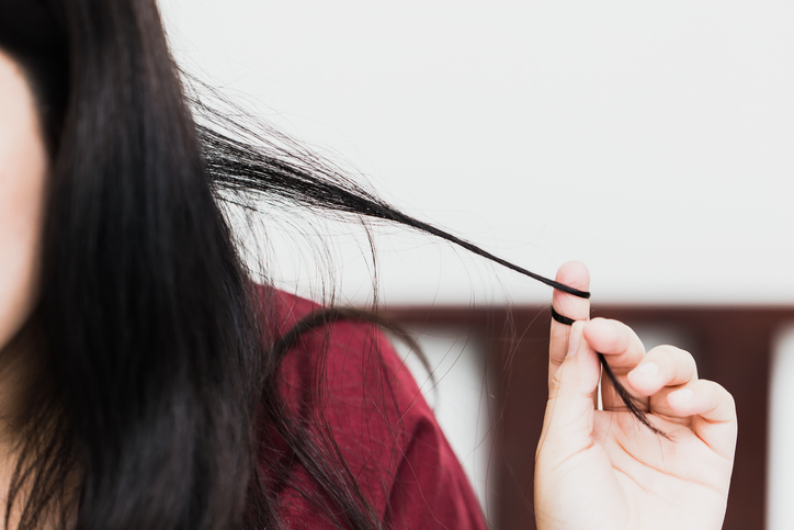 Close-up of a woman winding her long black hair around a finger.