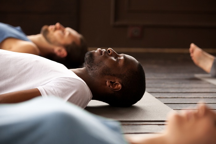 Men laying on their backs during a yoga class.