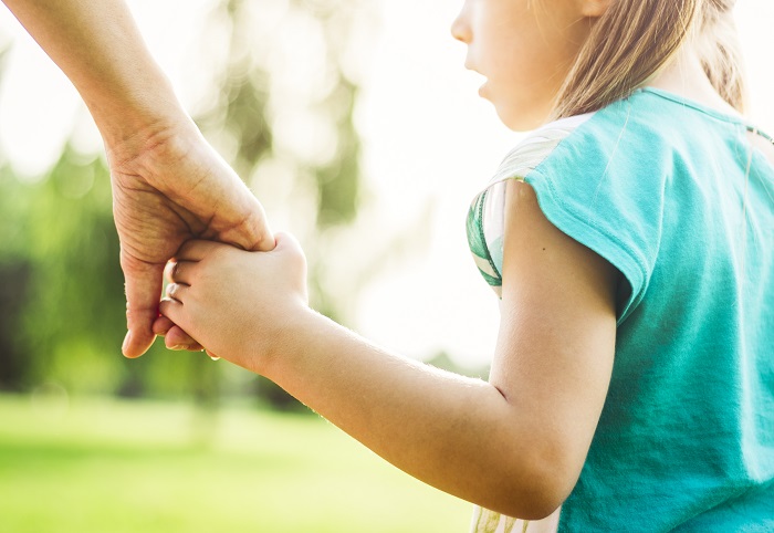 Parent holding young girl's hand