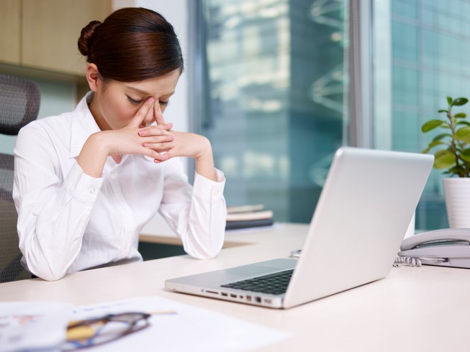 An office worker squeezes the bridge of her nose in frustration.