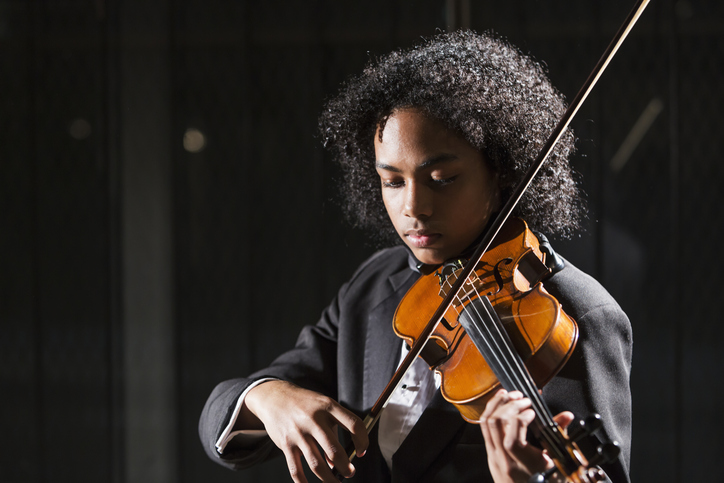 A young man performs a violin solo on stage.