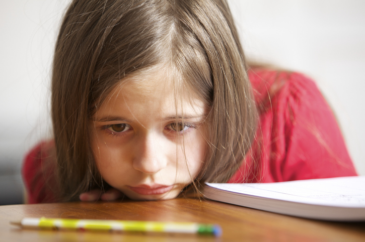 Girl with a frustrated expression glares at her pencil.