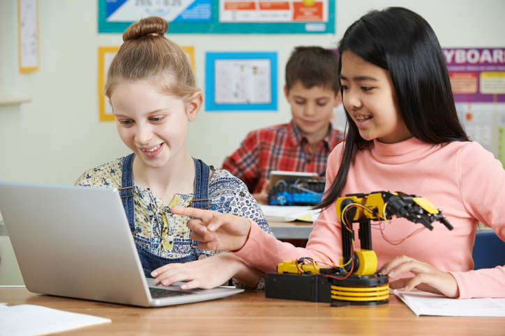 Two girls work together to build a robot arm.