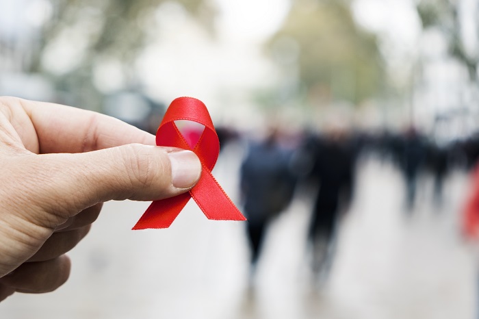 Hand holding AIDS awareness ribbon
