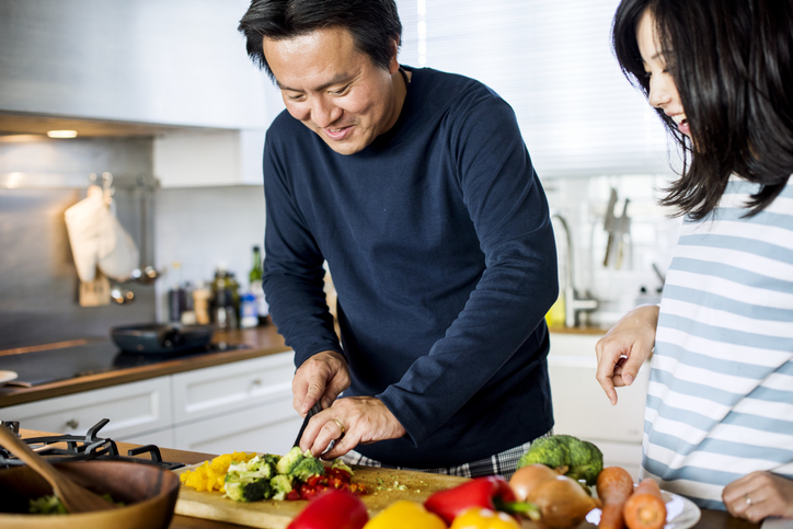 A middle-aged man chops up some peppers for dinner.