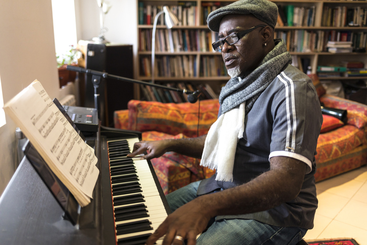 A composer works at the piano in his living room.