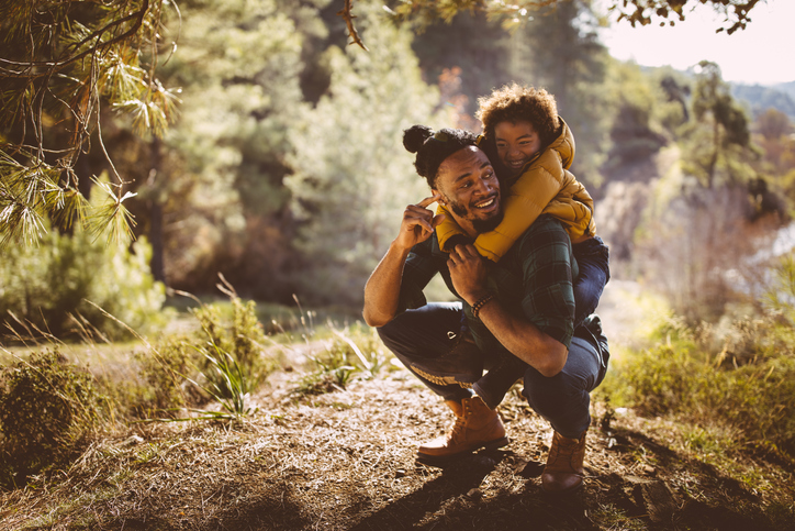 A father checks on his son during a forest hike.