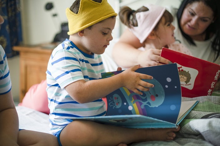 Boy wearing toy crown looks at picture book in a classroom