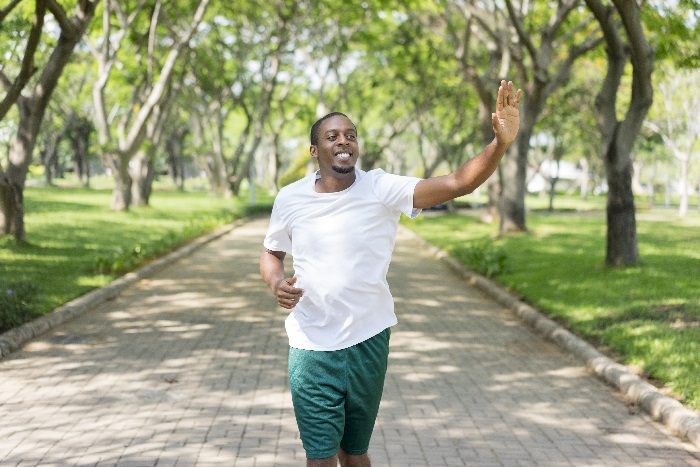 Man waving to friends while running in a park