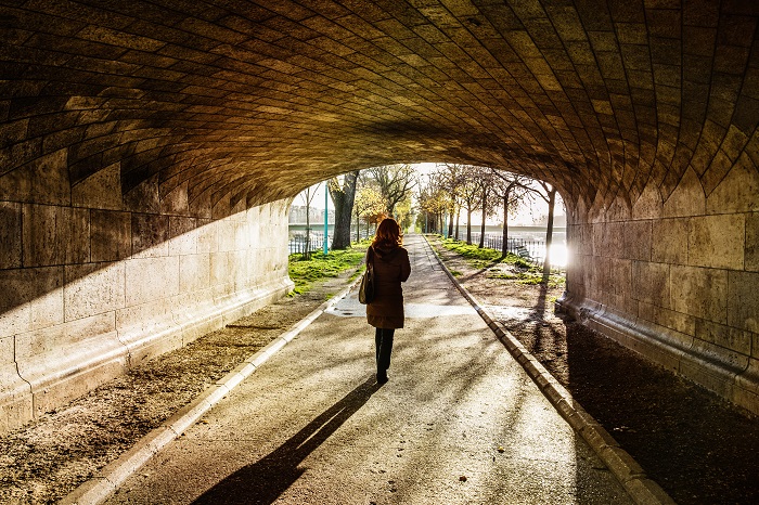 person walking under ached bridge