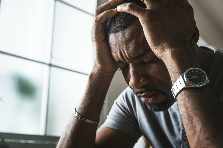 Overwhelmed man holds head in hands