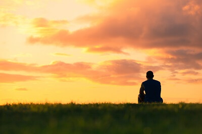 Silhouette of man watching the sun setting