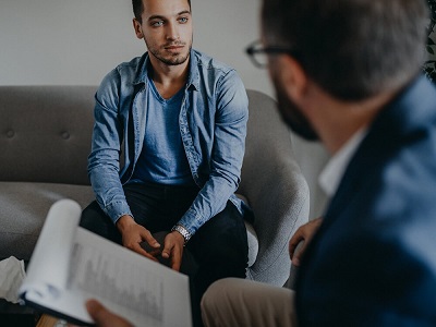 A counselor discusses this week's therapy homework with a man in blue.