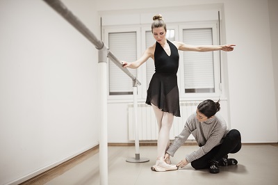 Dance instructor coaching ballerina on foot placement