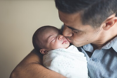 Father kissing his newborn baby