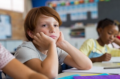 Boy sitting in class, looking deep in thought