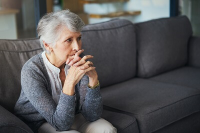 Mature woman sitting on a couch, deep in thought