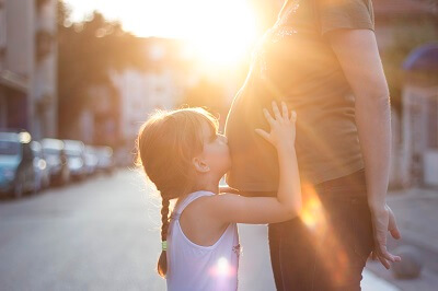 Little girl kissing her pregnant mother's stomach