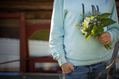 Person holding a bouquet of flowers, including daffodils