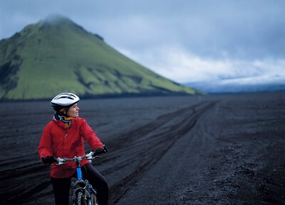 Woman biking on Icelandic black sand beach during her vacation