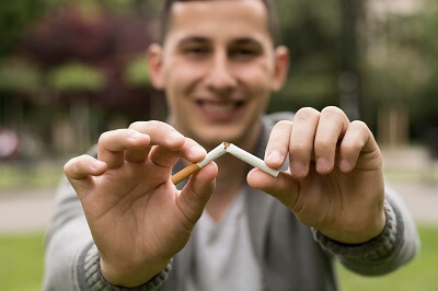 Happy man breaking a cigarette in half