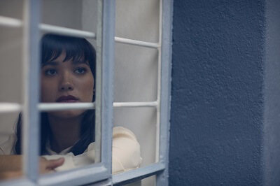 Anxious woman sitting behind window, looking outside