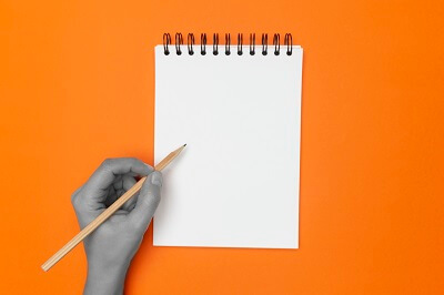 Hand writing on notepad with orange background