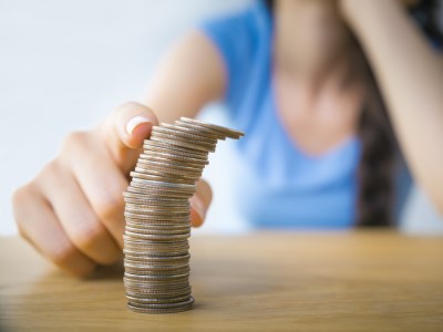 A finger topples a stack of coins.