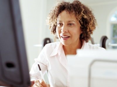 Therapist writes down notes while working at computer