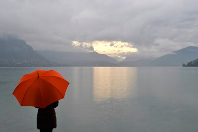 Person holding red umbrella, watching the horizon through mist