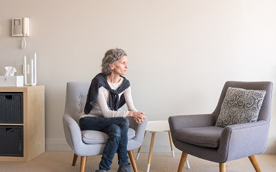 Therapist sitting next to empty chair, looking contemplative