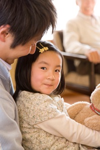 father and daughter with man seated in background observing