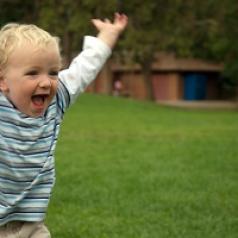 A toddler runs in a park. 
