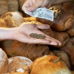 A market stallholder handing change to customer buying bread.