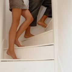 A couple walks upstairs, only their legs and feet showing.