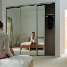 Woman is reflected in mirror while sitting on her bed thinking