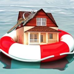 A miniature house floats in a life-preserver.