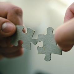 A close-up picture shows two puzzle pieces about to be placed together.
