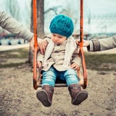 Toddler on a swing is pulled by parents on either side