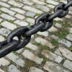 Links in a chain are shown hanging above a brick ground.