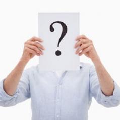 Man holding question mark in front of his face